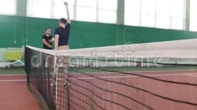 在网球场上训练。 年轻人在比赛前热身。 聚焦的网格和装满网球的手推车